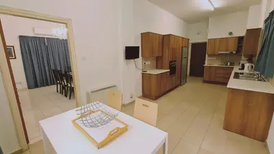 a kitchen with wooden cabinets and a white table at STAY Mythos Down Town House in Nicosia