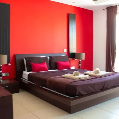 a bedroom with a large bed with red walls at Villa Artemis in Larnaka