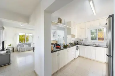 a large white kitchen with white cabinets and appliances at Protaras Fig Tree Bay Sea View Villa , Jacuzzi Available April to October in Protaras