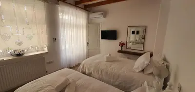 a white bedroom with two beds and a window at Bougainvillea House Lefkara in Pano Lefkara