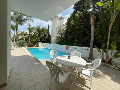 a patio with a table and chairs next to a pool at Zoe's villa by Turtle Bay in Protaras