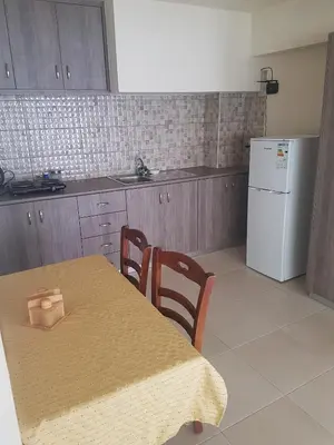 a kitchen with a table and a white refrigerator at Eleni Apartments in Ayia Napa