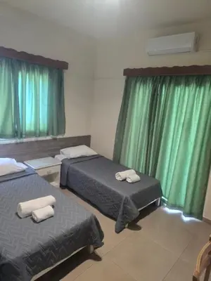 a hotel room with two beds and green curtains at Eleni Apartments in Ayia Napa