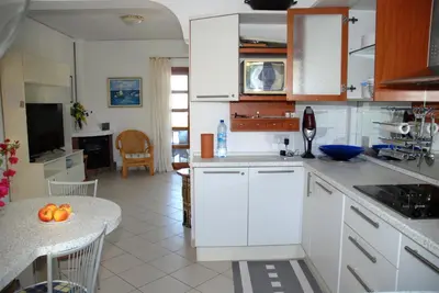a kitchen with white cabinets and a table with a bowl of fruit at Villa Hanna mit Meerblick in Pissouri