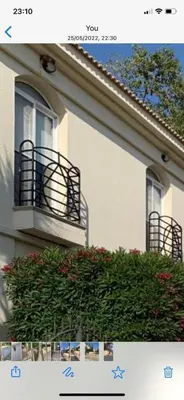 a white building with a balcony and a bush at Villa 28 Protaras in Protaras