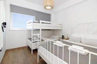 a bedroom with a bunk bed and two white chairs at Villa Selena in Protaras