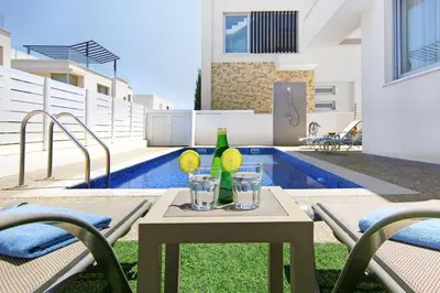 a table with two glasses and a bottle on it at Villa Selena in Protaras