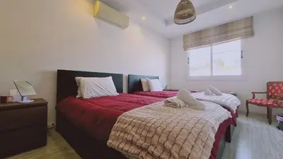 a bedroom with two beds with red sheets and a window at STAY Serenity Apartment in Yukarı Lakatamya