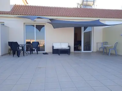 a patio with a blue umbrella and chairs and tables at Xylophagou Rest and Relax 2 Ayia Napa Larnaca 1 bedroom apartment in Xylophaghou