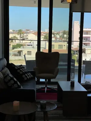 a living room with a chair and a large window at Unforgettable Experience in a Modern Apartment! in Larnaka