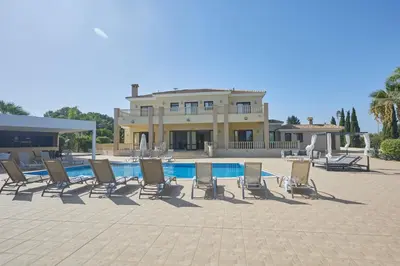 a group of chairs sitting next to a swimming pool at Protaras Holiday Villa Pa7 Private 7 Bedroom villa in Protaras