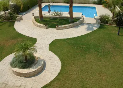 a walkway leading to a pool with a palm tree at Three bedroom villa with private pool and landscaped garden close to the beach in Pissouri