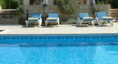 a group of blue chairs next to a swimming pool at Three bedroom villa with private pool and landscaped garden close to the beach in Pissouri