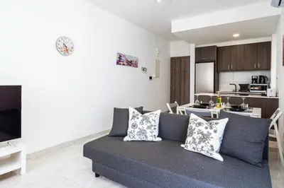 a living room with a couch and a kitchen at Lana 1-Bedroom Apt in Larnaca in Larnaka