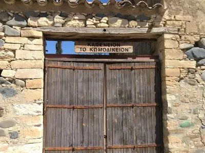 a wooden door in a stone building with a sign on it at Guesthouse Gonia in Pera Orinis