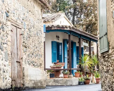 a stone building with blue shutters and potted plants at Guesthouse Gonia in Pera Orinis