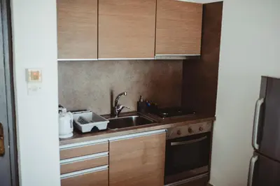 a kitchen with wooden cabinets and a sink at Ovis Hotel Apartments in Ayia Napa