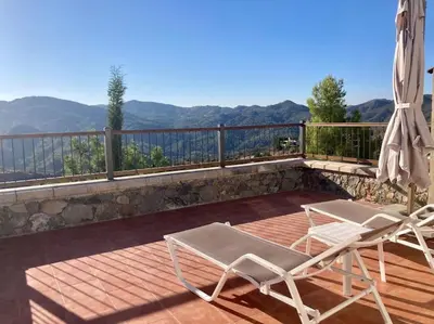 a pair of chairs and an umbrella on a deck at Traditional House with Mountain View - Dierona Village in Dierona