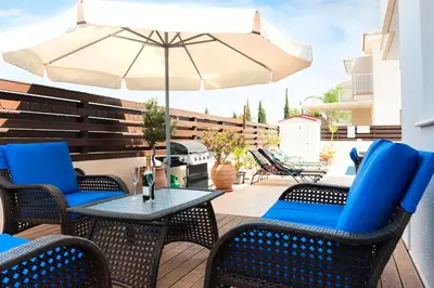 a patio with a table and chairs and an umbrella at VILLA ICARUS IN THE HEART OF PROTARAS in Protaras