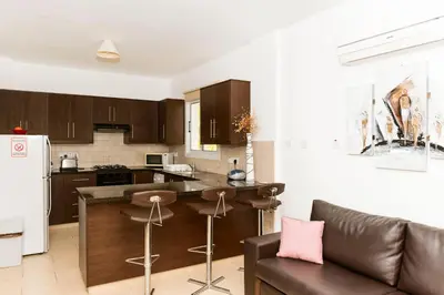 a kitchen with brown cabinets and a counter top at VILLA ICARUS IN THE HEART OF PROTARAS in Protaras