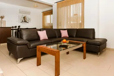 a living room with a black couch and a coffee table at VILLA ICARUS IN THE HEART OF PROTARAS in Protaras
