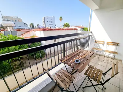 a balcony with a wooden bench and two chairs at Home Sweet Home Apartment in Larnaka