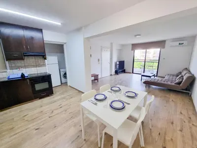 a kitchen and living room with a white table and chairs at Home Sweet Home Apartment in Larnaka
