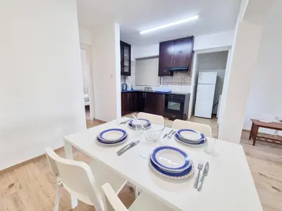 a dining room with a white table and chairs at Home Sweet Home Apartment in Larnaka