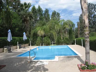 a swimming pool in a courtyard with a tree at Zena Holiday Villa in Pissouri