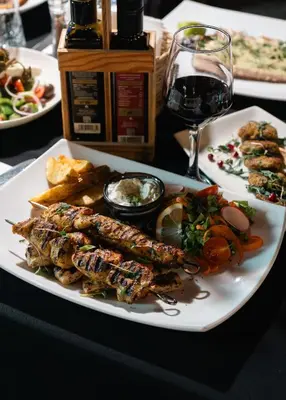 a plate of food on a table with a glass of wine at Pine View Boutique Hotel Adults Only in Saittas
