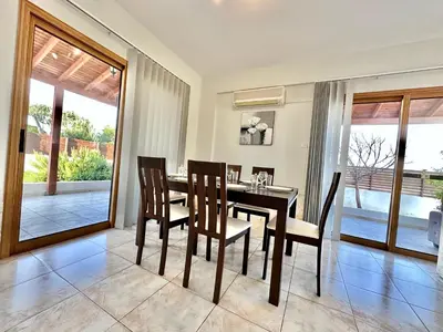 a dining room with a table and chairs and sliding glass doors at Lovely Pool Villa in Pyla in Pyla
