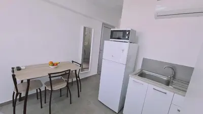 a kitchen with a small table and a white refrigerator at STAY Napa Living Studios in Ayia Napa