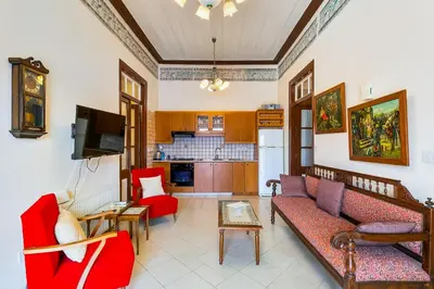 a living room with red furniture and a kitchen at Theodorou Stone House in Pano Lefkara
