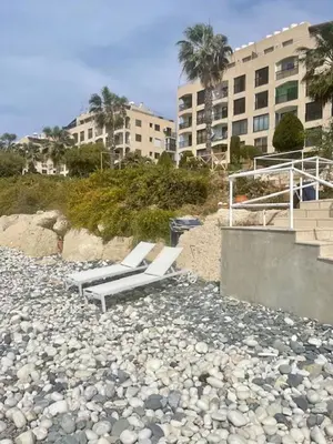 two lounge chairs on a rocky beach with a building at Seaside Studio Zygi in Zygi