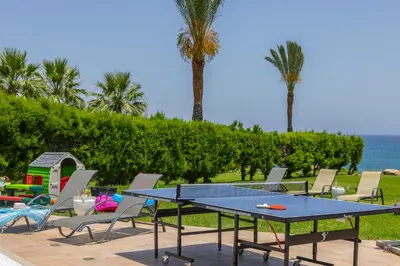 a ping pong table with chairs and the ocean at SunnyVillas: 4BR SeaFront Villa*Private Pool*BW44 in Protaras