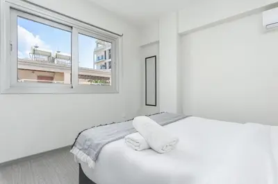 a white bedroom with a bed and a window at Amore 2-BR Apt By Finikoudes in Larnaka