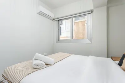 a white bedroom with a bed and a window at Amore 2-BR Apt By Finikoudes in Larnaka