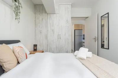 a white bedroom with a large bed and a refrigerator at Amore 2-BR Apt By Finikoudes in Larnaka