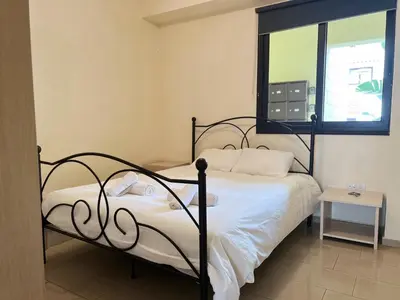 a bedroom with a bed with white sheets and a window at Antiparos 1 bedroom APT Kyklades in Paralimni