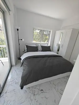 a large bed in a white bedroom with a window at Amalia Residences in Nicosia