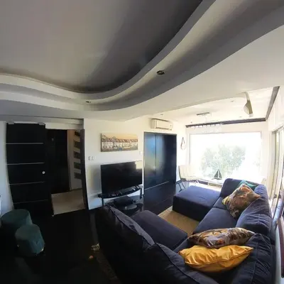 a living room with a couch and a tv at The View Beach Penthouse in Limassol