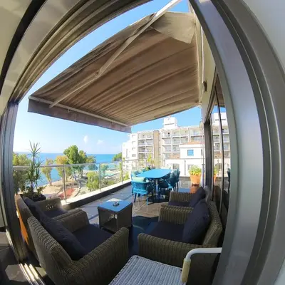 a room with chairs and a table and a balcony at The View Beach Penthouse in Limassol