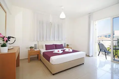 a white bedroom with a bed and a balcony at Villa Adonia - 30m from Pernera Beach in Protaras