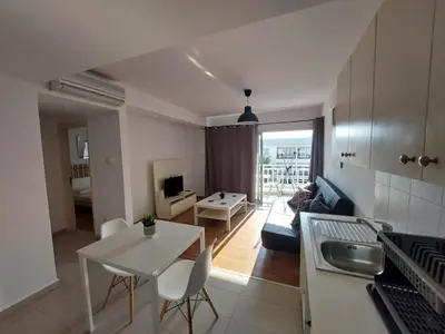a kitchen and living room with a white table and chairs at Sunny Breeze in Ayia Napa