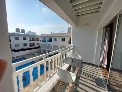 a balcony with a table and chairs and a pool at Sunny Breeze in Ayia Napa