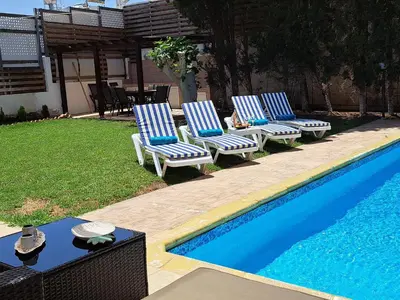 three blue and white chairs next to a swimming pool at VILLA MARINA BY FIG TREE BAY in Protaras