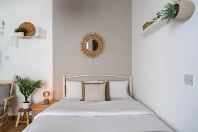 a bedroom with a bed with white sheets and a mirror at Orchid's Cozy Studio & Balcony in Larnaca in Larnaka