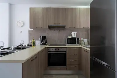 a kitchen with wooden cabinets and a stove top oven at A Blissful 1-Bedroom Voyage in Larnaca in Larnaka