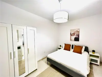 a white bedroom with a bed and a mirror at LINA 25 in Larnaka