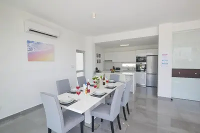 a white dining room with a white table and chairs at Protaras Olivine Villa Ol01 in Paralimni